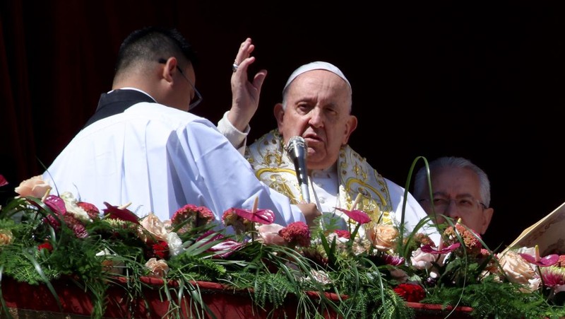 Paus Fransiskus melambai dari loggia Basilika Santo Petrus yang menghadap ke alun-alun Santo Petrus, setelah menyampaikan berkat Paskah Urbi et Orbi pada 9 April 2023 di Vatikan. (ANDREAS SOLARO/AFP via Getty Images)