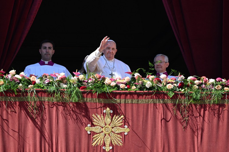 Paus Fransiskus melambai dari loggia Basilika Santo Petrus yang menghadap ke alun-alun Santo Petrus, setelah menyampaikan berkat Paskah Urbi et Orbi pada 9 April 2023 di Vatikan. Paus Fransiskus melambai dari loggia Basilika Santo Petrus yang menghadap ke alun-alun Santo Petrus, setelah menyampaikan berkat Paskah Urbi et Orbi pada 9 April 2023 di Vatikan. (ANDREAS SOLARO/AFP via Getty Images)