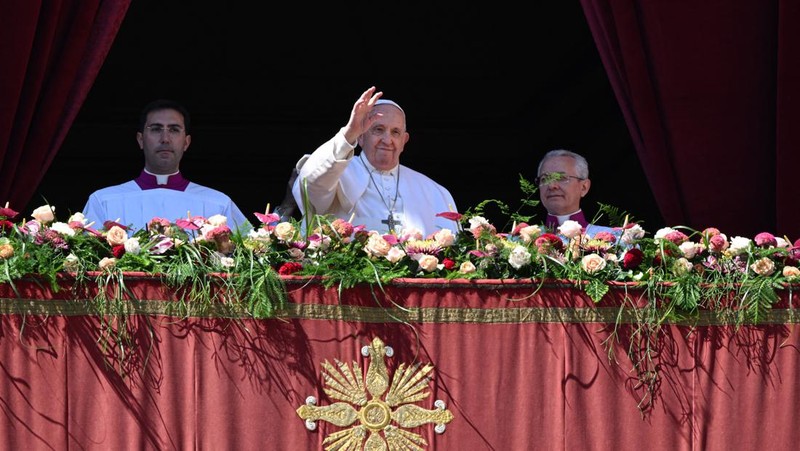 Paus Fransiskus melambai dari loggia Basilika Santo Petrus yang menghadap ke alun-alun Santo Petrus, setelah menyampaikan berkat Paskah Urbi et Orbi pada 9 April 2023 di Vatikan. (ANDREAS SOLARO/AFP via Getty Images)