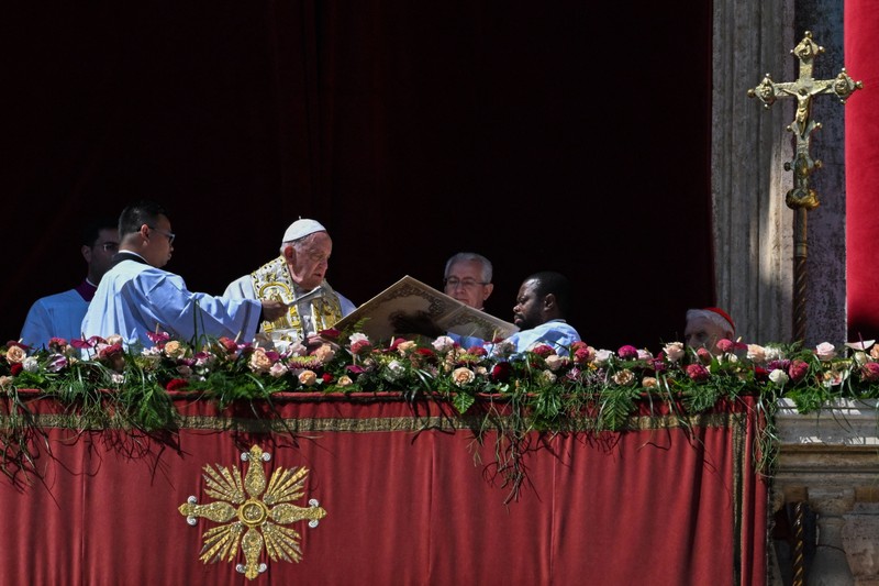 Paus Fransiskus melambai dari loggia Basilika Santo Petrus yang menghadap ke alun-alun Santo Petrus, setelah menyampaikan berkat Paskah Urbi et Orbi pada 9 April 2023 di Vatikan. (ANDREAS SOLARO/AFP via Getty Images)