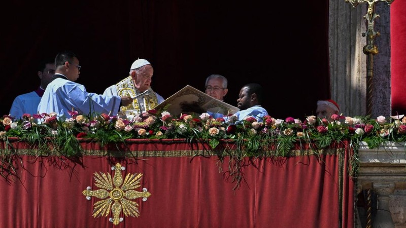 Paus Fransiskus melambai dari loggia Basilika Santo Petrus yang menghadap ke alun-alun Santo Petrus, setelah menyampaikan berkat Paskah Urbi et Orbi pada 9 April 2023 di Vatikan. (ANDREAS SOLARO/AFP via Getty Images)
