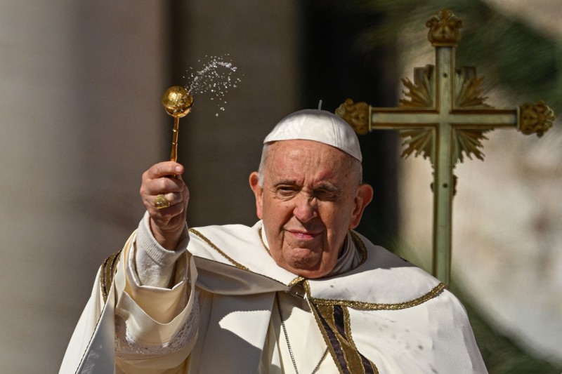 Paus Fransiskus melambai dari loggia Basilika Santo Petrus yang menghadap ke alun-alun Santo Petrus, setelah menyampaikan berkat Paskah Urbi et Orbi pada 9 April 2023 di Vatikan. (ANDREAS SOLARO/AFP via Getty Images)