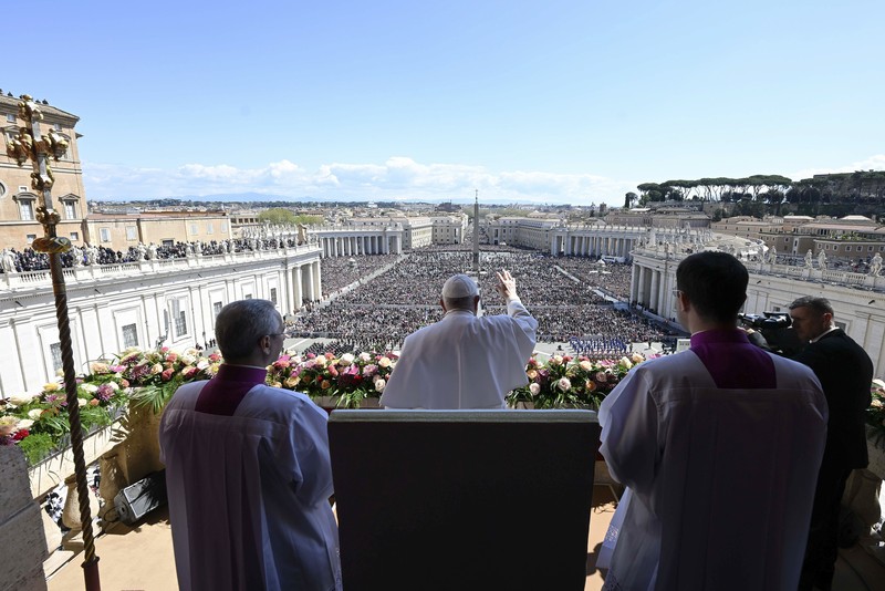 Paus Fransiskus melambai dari loggia Basilika Santo Petrus yang menghadap ke alun-alun Santo Petrus, setelah menyampaikan berkat Paskah Urbi et Orbi pada 9 April 2023 di Vatikan. Paus Fransiskus melambai dari loggia Basilika Santo Petrus yang menghadap ke alun-alun Santo Petrus, setelah menyampaikan berkat Paskah Urbi et Orbi pada 9 April 2023 di Vatikan. (ANDREAS SOLARO/AFP via Getty Images)