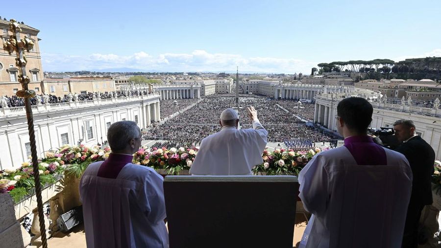 Paus Fransiskus melambai dari loggia Basilika Santo Petrus yang menghadap ke alun-alun Santo Petrus, setelah menyampaikan berkat Paskah Urbi et Orbi pada 9 April 2023 di Vatikan. (ANDREAS SOLARO/AFP via Getty Images)
