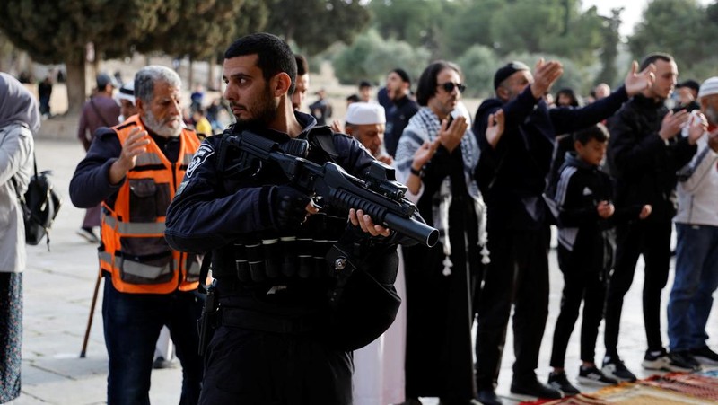 Pengunjung Yahudi berjalan melewati orang-orang yang membaca Alquran, di kompleks Masjid Al-Aqsa, yang dikenal umat Islam sebagai Tempat Suci Mulia dan bagi orang Yahudi sebagai Temple Mount, sementara ketegangan muncul selama bentrokan di Kota Tua Yerusalem, 9 April 2023. (REUTERS/Ammar Awad)