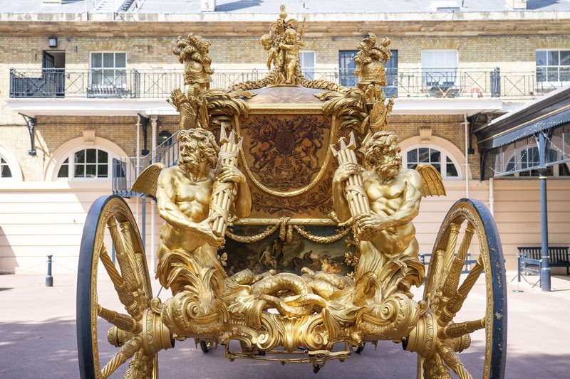 King Charles III Coronation The Diamond Jubilee State Coach on display at the Royal Mews in Buckingham Palace, London, Tuesday April 4, 2023, in which King Charles III and the Queen Consort will travel to the coronation. King Charles III is taking a short cut and smoother ride to Westminster Abbey, trimming the procession route his mother took in 1953 as he aims for a more modest coronation that will include some modern touches, Buckingham Palace said Sunday April 9, 2023. (Yui Mok/PA via AP)