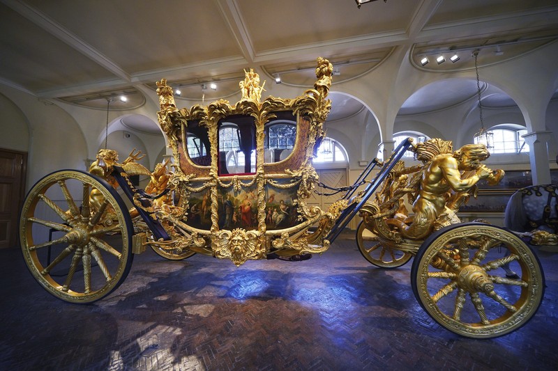 King Charles III Coronation The Diamond Jubilee State Coach on display at the Royal Mews in Buckingham Palace, London, Tuesday April 4, 2023, in which King Charles III and the Queen Consort will travel to the coronation. King Charles III is taking a short cut and smoother ride to Westminster Abbey, trimming the procession route his mother took in 1953 as he aims for a more modest coronation that will include some modern touches, Buckingham Palace said Sunday April 9, 2023. (Yui Mok/PA via AP)