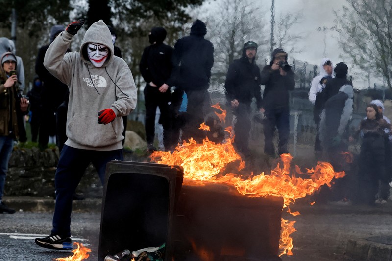 Pembangkang republik melemparkan bom bensin ke mobil polisi setelah unjuk rasa anti-Perjanjian Jumat Agung pada peringatan 25 tahun perjanjian damai, di Londonderry, Irlandia Utara, 10 April 2023. Pembangkang republik melemparkan bom bensin ke mobil polisi setelah unjuk rasa anti-Perjanjian Jumat Agung pada peringatan 25 tahun perjanjian damai, di Londonderry, Irlandia Utara, 10 April 2023. (REUTERS/Clodagh Kilcoyne)