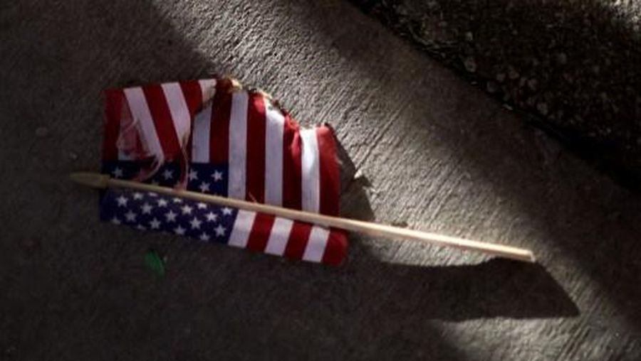BROOKLYN CENTER, MINNESOTA - APRIL 16: An partially-burned American flag lays on the ground during a protest outside the Brooklyn Center police station on April 16, 2021 in Brooklyn Center, Minnesota. This is the sixth day of protests in the suburban Minneapolis city following the fatal shooting of 20-year-old Daunte Wright by Brooklyn Center police officer Kimberly Potter, who has since resigned from the force and been charged with second-degree manslaughter for the shooting. Scott Olson/Getty Images/AFP (Photo by SCOTT OLSON / GETTY IMAGES NORTH AMERICA / Getty Images via AFP)