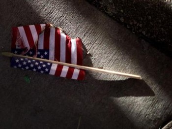 BROOKLYN CENTER, MINNESOTA - APRIL 16: An partially-burned American flag lays on the ground during a protest outside the Brooklyn Center police station on April 16, 2021 in Brooklyn Center, Minnesota. This is the sixth day of protests in the suburban