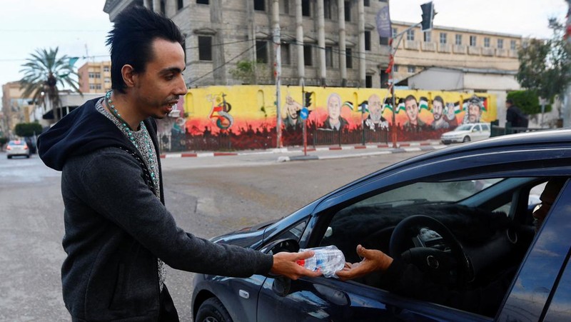 Seorang pria Kristen Palestina Ehab Ayyad menawarkan kurma dan air kepada umat Islam yang terjebak kemacetan atau terlambat pulang untuk berbuka puasa selama Ramadhan, di Kota Gaza 12 April 2023. (REUTERS/Ibraheem Abu Mustafa)