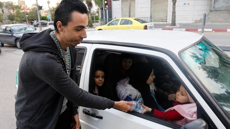 Seorang pria Kristen Palestina Ehab Ayyad menawarkan kurma dan air kepada umat Islam yang terjebak kemacetan atau terlambat pulang untuk berbuka puasa selama Ramadhan, di Kota Gaza 12 April 2023. (REUTERS/Ibraheem Abu Mustafa)