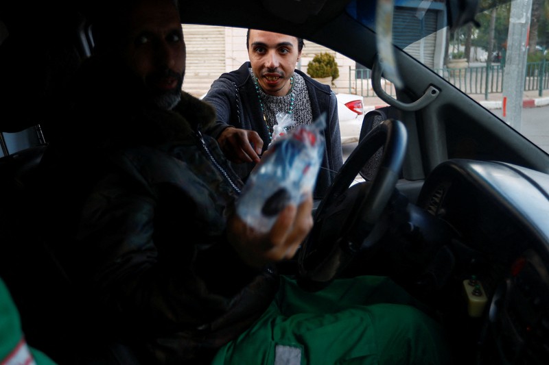 Seorang pria Kristen Palestina Ehab Ayyad menawarkan kurma dan air kepada umat Islam yang terjebak kemacetan atau terlambat pulang untuk berbuka puasa selama Ramadhan, di Kota Gaza 12 April 2023. (REUTERS/Ibraheem Abu Mustafa)