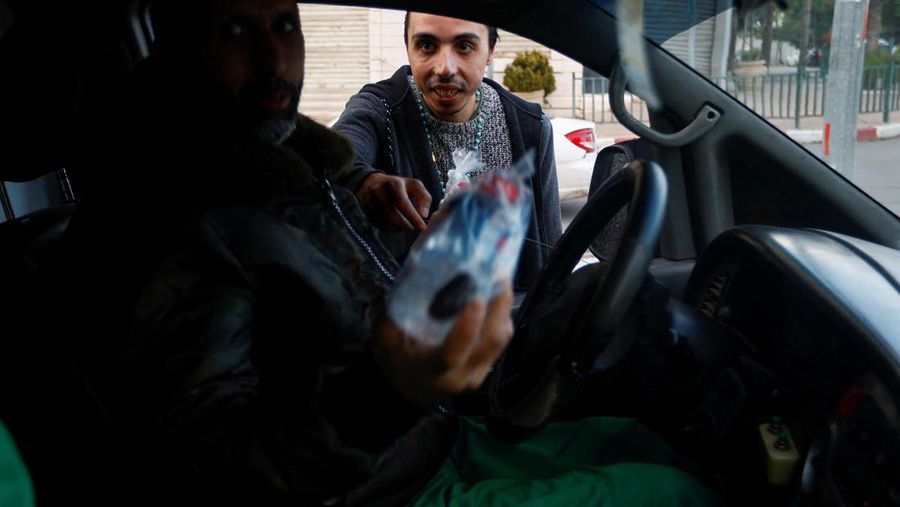 Seorang pria Kristen Palestina Ehab Ayyad menawarkan kurma dan air kepada umat Islam yang terjebak kemacetan atau terlambat pulang untuk berbuka puasa selama Ramadhan, di Kota Gaza 12 April 2023. (REUTERS/Ibraheem Abu Mustafa)