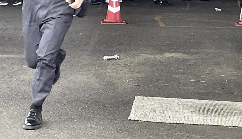 Seorang pria, diyakini sebagai tersangka yang melemparkan benda mirip pipa di dekat Perdana Menteri Jepang Fumio Kishida selama pidatonya di luar ruangan. (TWITTER @AK2364N via REUTERS)