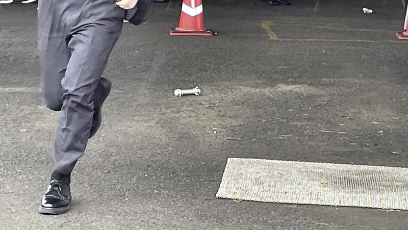 Seorang pria, diyakini sebagai tersangka yang melemparkan benda mirip pipa di dekat Perdana Menteri Jepang Fumio Kishida selama pidatonya di luar ruangan. (TWITTER @AK2364N via REUTERS)