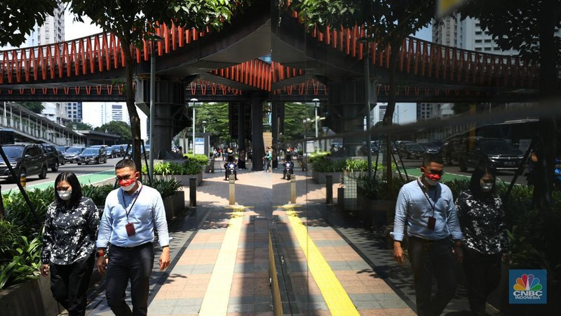 Warga menggunakan payung untuk menghindari paparan sinar matahari di kawasan Jakarta, Senin (17/4/2023). (CNBC Indonesia/Tri Susilo)