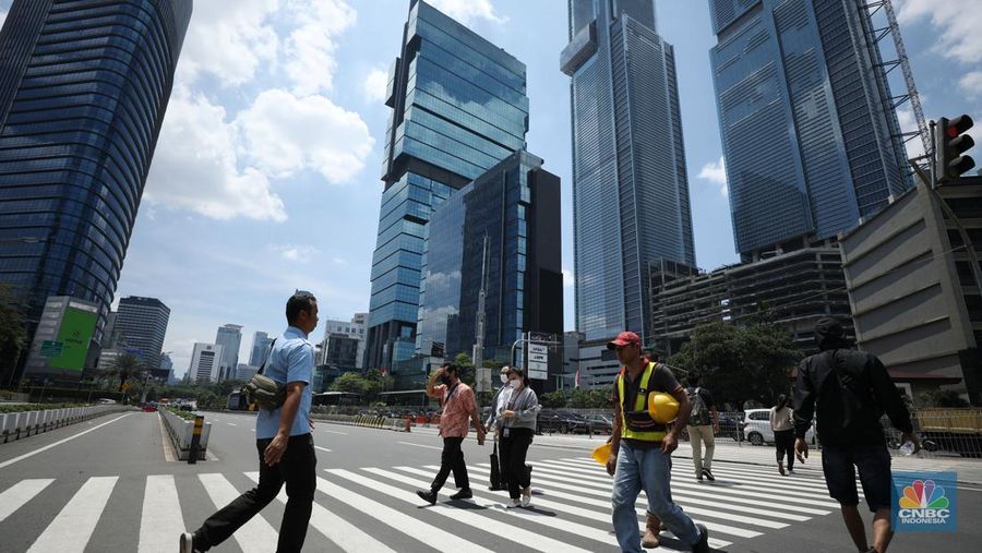 Warga menggunakan payung untuk menghindari paparan sinar matahari di kawasan Jakarta, Senin (17/4/2023). (CNBC Indonesia/Tri Susilo)