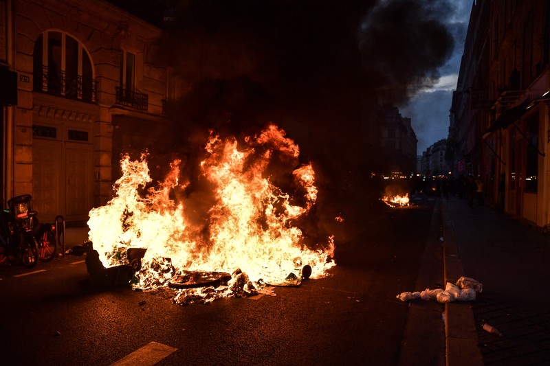 Para pengunjuk rasa berkumpul ketika seorang demonstran memegang topeng yang menggambarkan Presiden Prancis Emmanuel Macron dan berpakaian seperti seorang raja, selama demonstrasi menyusul pidato khusus kepada negara oleh Macron, setelah dia menandatangani undang-undang reformasi pensiun yang menaikkan usia pensiun, di Paris, Prancis, 17 April 2023. Para pengunjuk rasa berkumpul ketika seorang demonstran memegang topeng yang menggambarkan Presiden Prancis Emmanuel Macron dan berpakaian seperti seorang raja, selama demonstrasi menyusul pidato khusus kepada negara oleh Macron, setelah dia menandatangani undang-undang reformasi pensiun yang menaikkan usia pensiun, di Paris, Prancis, 17 April 2023. (REUTERS/Stephanie Lecocq)