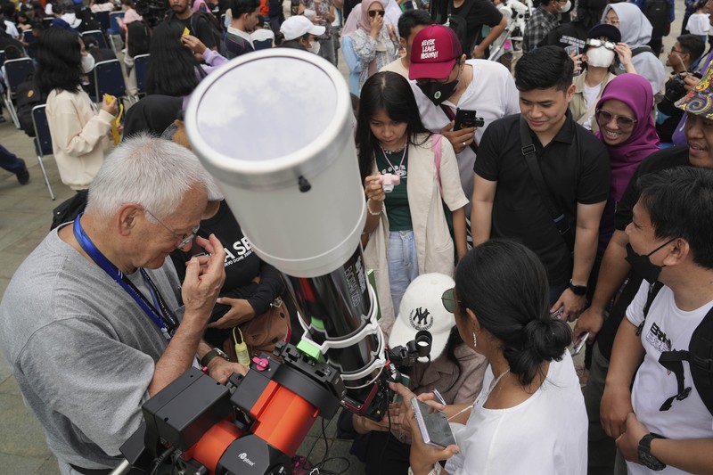 Warga menggunakan kacamata pelindung untuk menyaksikan gerhana matahari di Jakarta, Indonesia, Kamis, 20 April 2023. (AP/Tatan Syuflana)