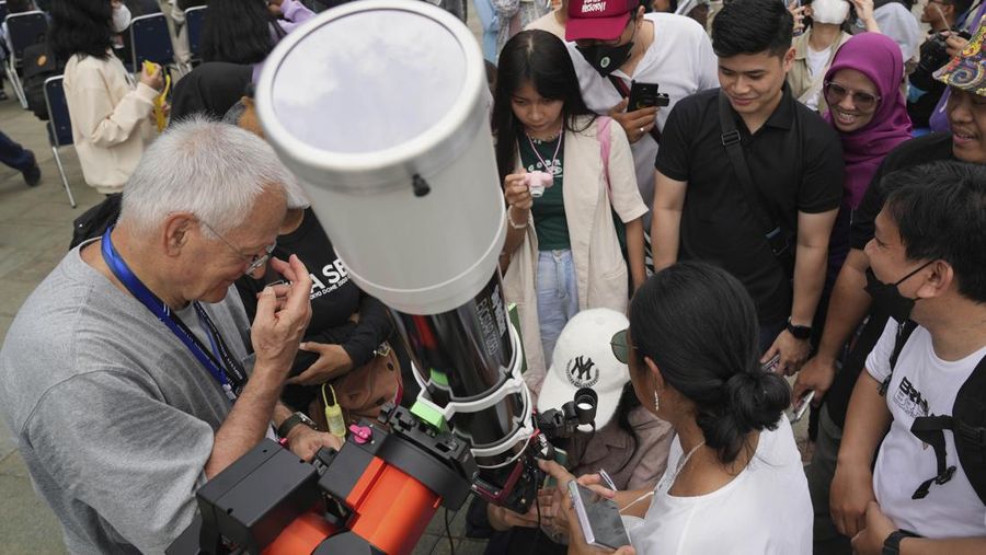 Warga menggunakan kacamata pelindung untuk menyaksikan gerhana matahari di Jakarta, Indonesia, Kamis, 20 April 2023. (AP/Tatan Syuflana)
