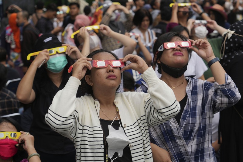 Warga menggunakan kacamata pelindung untuk menyaksikan gerhana matahari di Jakarta, Indonesia, Kamis, 20 April 2023. (AP/Tatan Syuflana)