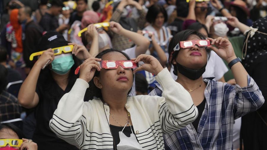 Warga menggunakan kacamata pelindung untuk menyaksikan gerhana matahari di Jakarta, Indonesia, Kamis, 20 April 2023. (AP/Tatan Syuflana)