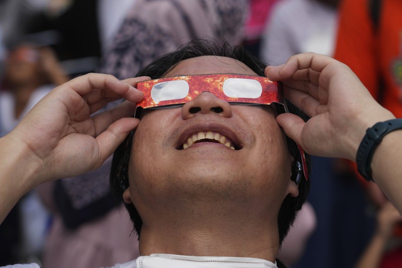 Warga menggunakan kacamata pelindung untuk menyaksikan gerhana matahari di Jakarta, Indonesia, Kamis, 20 April 2023. (AP/Tatan Syuflana)