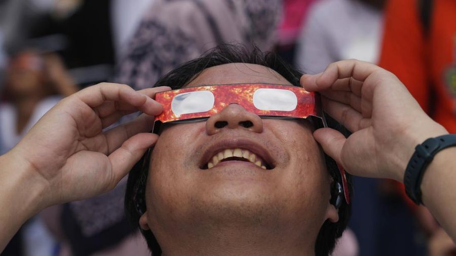 Warga menggunakan kacamata pelindung untuk menyaksikan gerhana matahari di Jakarta, Indonesia, Kamis, 20 April 2023. (AP/Tatan Syuflana)