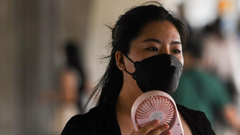 Seorang wanita menggunakan kipas tangan saat suhu mencapai rekor 45,4 derajat Celcius (113,7 Fahrenheit) di Bangkok, Thailand, 22 April 2023. (REUTERS/Chalinee Thirasupa)