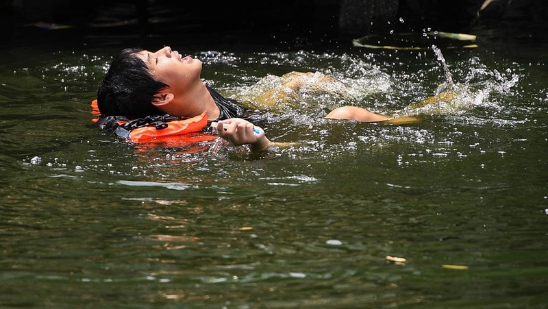 Orang-orang memegang payung saat menyeberang jalan saat suhu mencapai rekor 45,4 derajat Celcius (113,7 Fahrenheit) di Bangkok, Thailand, 22 April 2023. (REUTERS/Chalinee Thirasupa)