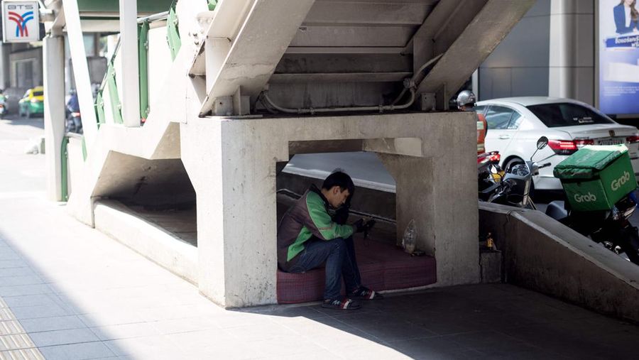 A motorbike delivery driver shelters from the sun by the side of the road during heatwave conditions in Bangkok on April 20, 2023. - Sweltering under a blistering sun, people across South and Southeast Asia have been taking cover beneath any shelter they can find as they pray for cooling rains with record temperatures hitting the region. (Photo by Jack TAYLOR / AFP) (Photo by JACK TAYLOR/AFP via Getty Images)