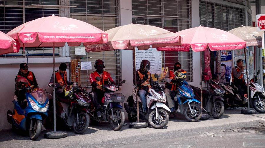 Motorbike taxi drivers shelter from the sun under umbrellas during heatwave conditions in Bangkok on April 20, 2023. - Sweltering under a blistering sun, people across South and Southeast Asia have been taking cover beneath any shelter they can find as they pray for cooling rains with record temperatures hitting the region. (Photo by Jack TAYLOR / AFP) (Photo by JACK TAYLOR/AFP via Getty Images)