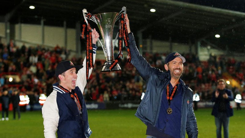 Soccer Football - National League - Wrexham v Boreham Wood - Racecourse Ground, Wrexham, Britain - April 22, 2023 Wrexham co-owners Rob McElhenney and Ryan Reynolds celebrate with the trophy on the pitch after Wrexham win the National League and promotion to League Two Action Images via Reuters/Ed Sykes EDITORIAL USE ONLY. No use with unauthorized audio, video, data, fixture lists, club/league logos or 'live' services. Online in-match use limited to 75 images, no video emulation. No use in betting, games or single club /league/player publications.  Please contact your account representative for further details.     TPX IMAGES OF THE DAY