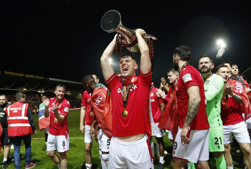 Soccer Football - National League - Wrexham v Boreham Wood - Racecourse Ground, Wrexham, Britain - April 22, 2023 Wrexham co-owners Rob McElhenney and Ryan Reynolds celebrate with the trophy on the pitch after Wrexham win the National League and promotion to League Two Action Images via Reuters/Ed Sykes EDITORIAL USE ONLY. No use with unauthorized audio, video, data, fixture lists, club/league logos or 'live' services. Online in-match use limited to 75 images, no video emulation. No use in betting, games or single club /league/player publications.  Please contact your account representative for further details.     TPX IMAGES OF THE DAY