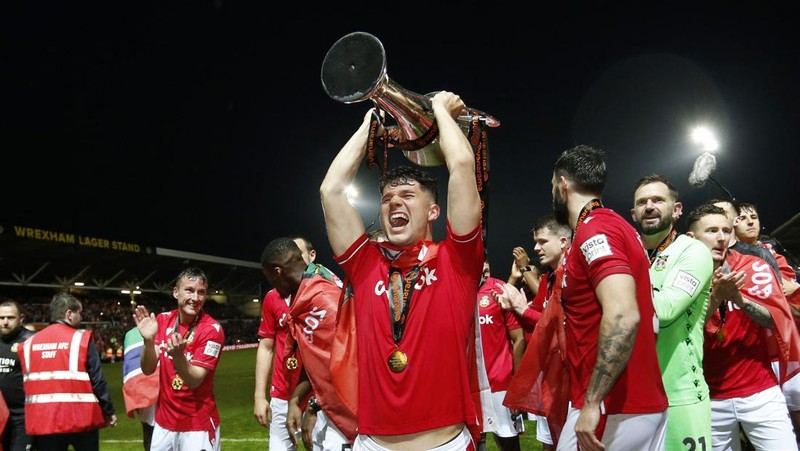 Soccer Football - National League - Wrexham v Boreham Wood - Racecourse Ground, Wrexham, Britain - April 22, 2023 Wrexham co-owners Rob McElhenney and Ryan Reynolds celebrate with the trophy on the pitch after Wrexham win the National League and promotion to League Two Action Images via Reuters/Ed Sykes EDITORIAL USE ONLY. No use with unauthorized audio, video, data, fixture lists, club/league logos or 'live' services. Online in-match use limited to 75 images, no video emulation. No use in betting, games or single club /league/player publications.  Please contact your account representative for further details.     TPX IMAGES OF THE DAY