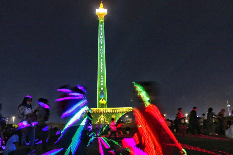 Pengunjung menyaksikan tayangan video mapping di kawasan Monas Jakarta Indonesia pada 23 April 2023. Bertepatan dengan libur Idul Fitri, Pemprov DKI Jakarta menggelar Pekan Kegiatan Monas 2023 yang ditandai dengan tayangan video mapping. (Eko Siswono Toyudho/Anadolu Agency via Getty Images)