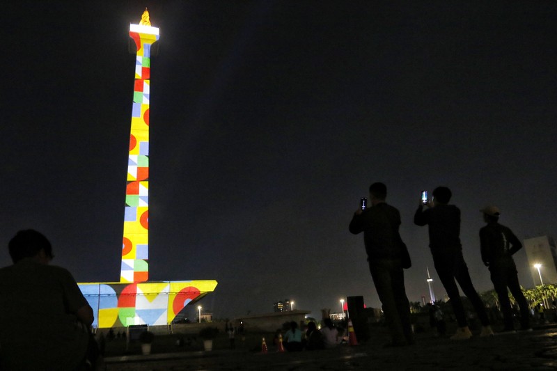 Pengunjung menyaksikan tayangan video mapping di kawasan Monas Jakarta Indonesia pada 23 April 2023. Bertepatan dengan libur Idul Fitri, Pemprov DKI Jakarta menggelar Pekan Kegiatan Monas 2023 yang ditandai dengan tayangan video mapping. (Eko Siswono Toyudho/Anadolu Agency via Getty Images)