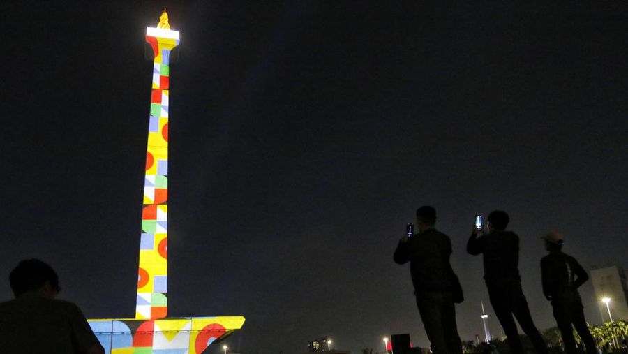 Pengunjung menyaksikan tayangan video mapping di kawasan Monas Jakarta Indonesia pada 23 April 2023. Bertepatan dengan libur Idul Fitri, Pemprov DKI Jakarta menggelar Pekan Kegiatan Monas 2023 yang ditandai dengan tayangan video mapping. (Eko Siswono Toyudho/Anadolu Agency via Getty Images)