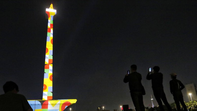 Pengunjung menyaksikan tayangan video mapping di kawasan Monas Jakarta Indonesia pada 23 April 2023. Bertepatan dengan libur Idul Fitri, Pemprov DKI Jakarta menggelar Pekan Kegiatan Monas 2023 yang ditandai dengan tayangan video mapping. (Eko Siswono Toyudho/Anadolu Agency via Getty Images)