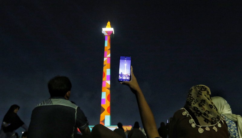 Pengunjung menyaksikan tayangan video mapping di kawasan Monas Jakarta Indonesia pada 23 April 2023. Pengunjung menyaksikan tayangan video mapping di kawasan Monas Jakarta Indonesia pada 23 April 2023. Bertepatan dengan libur Idul Fitri, Pemprov DKI Jakarta menggelar Pekan Kegiatan Monas 2023 yang ditandai dengan tayangan video mapping. (Eko Siswono Toyudho/Anadolu Agency via Getty Images)