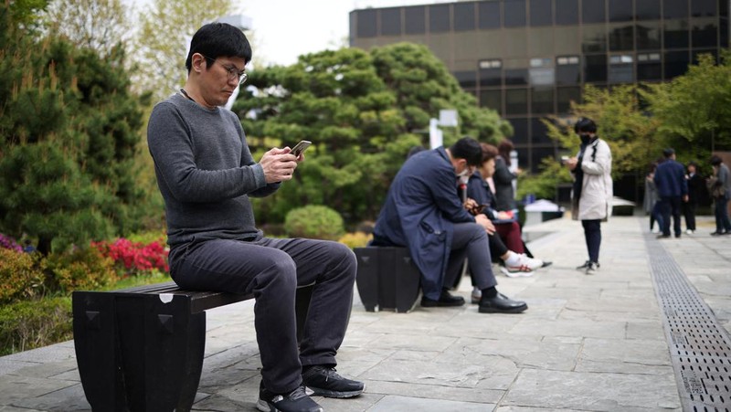 Office workers look at their mobile phones to check the local online banking app Toss as they gather at Seoul Museum of Art during a lunch break in Seoul, South Korea, April 13, 2023.  REUTERS/Kim Hong-Ji