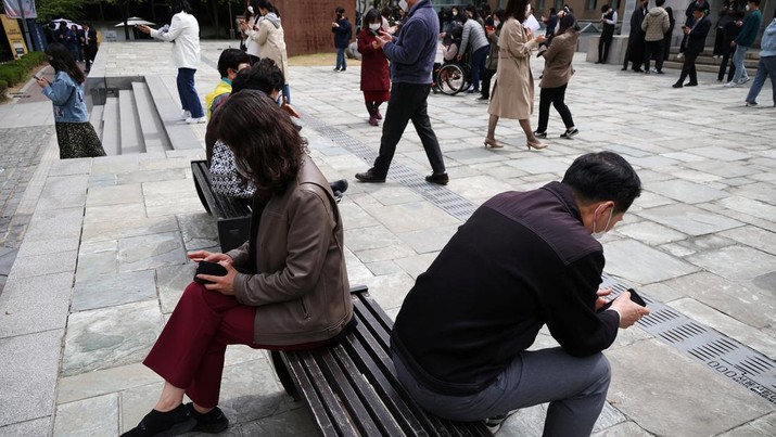 Office workers look at their mobile phones to check the local online banking app Toss as they gather at Seoul Museum of Art during a lunch break in Seoul, South Korea, April 13, 2023.  REUTERS/Kim Hong-Ji