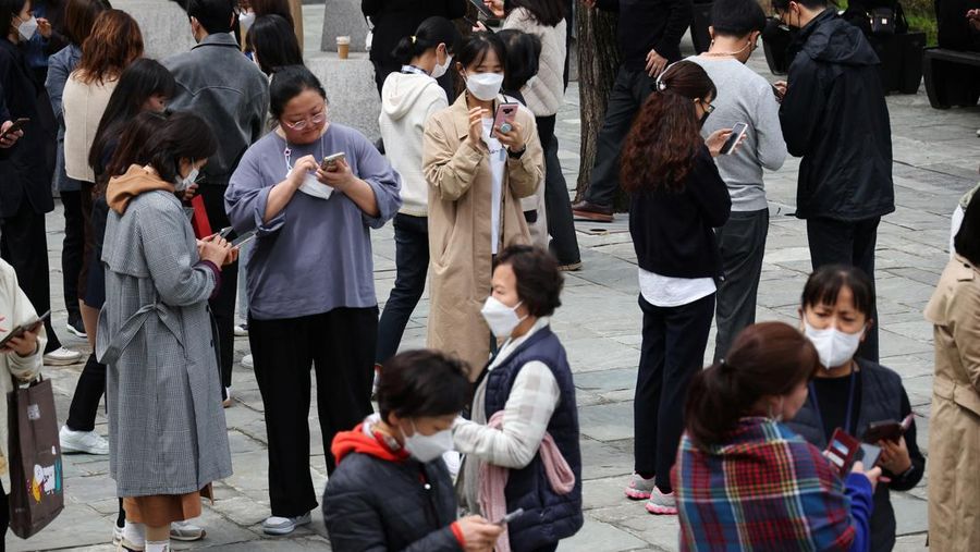 Office workers look at their mobile phones to check the local online banking app Toss as they gather at Seoul Museum of Art during a lunch break in Seoul, South Korea, April 13, 2023.  REUTERS/Kim Hong-Ji