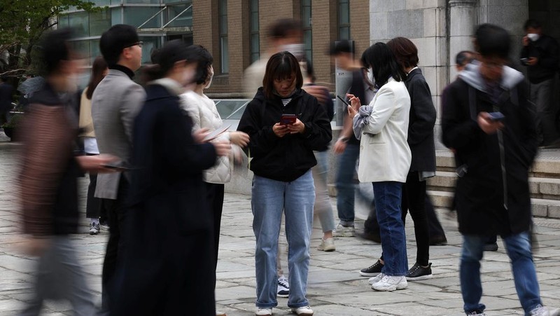 Office workers look at their mobile phones to check the local online banking app Toss as they gather at Seoul Museum of Art during a lunch break in Seoul, South Korea, April 13, 2023.  REUTERS/Kim Hong-Ji
