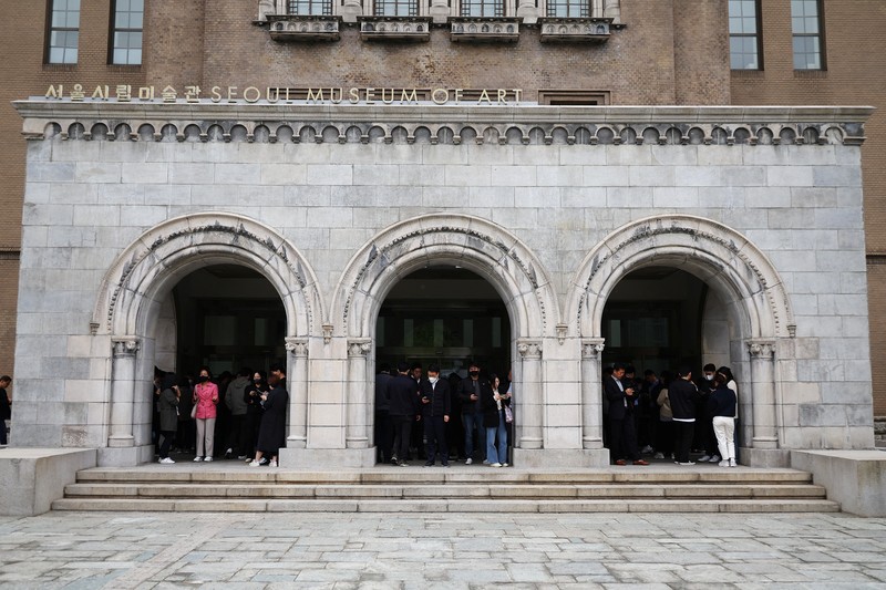 Office workers look at their mobile phones to check the local online banking app Toss as they gather at Seoul Museum of Art during a lunch break in Seoul, South Korea, April 13, 2023.  REUTERS/Kim Hong-Ji