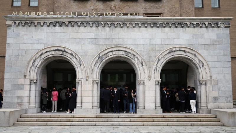 Office workers look at their mobile phones to check the local online banking app Toss as they gather at Seoul Museum of Art during a lunch break in Seoul, South Korea, April 13, 2023.  REUTERS/Kim Hong-Ji