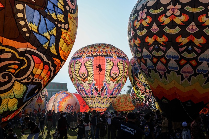 WONOSOBO, INDONESIA - APRIL 23: Hot air balloons fly over the sky during a balloon festival on the Eid al-Fitr holiday at Ronggolawe Stadion on April 23, 2023, in Wonosobo, Central Java, Indonesia. Javanese people fly giant hot air balloons during Eid, which has long been a tradition of the Wonosobo regency. (Photo by Garry Lotulung/Anadolu Agency via Getty Images)