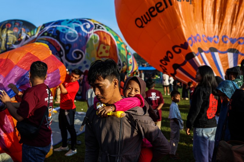 1252105442 WONOSOBO, INDONESIA - APRIL 23: Hot air balloons fly over the sky during a balloon festival on the Eid al-Fitr holiday at Ronggolawe Stadion on April 23, 2023, in Wonosobo, Central Java, Indonesia. Javanese people fly giant hot air balloons during Eid, which has long been a tradition of the Wonosobo regency. (Photo by Garry Lotulung/Anadolu Agency via Getty Images)