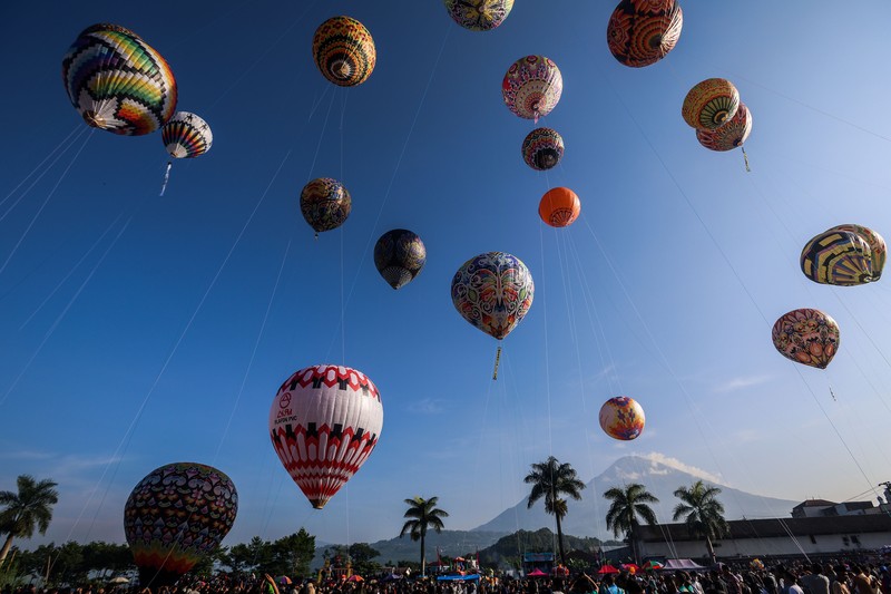 WONOSOBO, INDONESIA - APRIL 23: Hot air balloons fly over the sky during a balloon festival on the Eid al-Fitr holiday at Ronggolawe Stadion on April 23, 2023, in Wonosobo, Central Java, Indonesia. Javanese people fly giant hot air balloons during Eid, which has long been a tradition of the Wonosobo regency. (Photo by Garry Lotulung/Anadolu Agency via Getty Images)